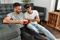 Two hispanic men couple using smartphone and drinking coffee at home Royalty Free Stock Photo