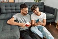 Two hispanic men couple using smartphone and drinking coffee at home Royalty Free Stock Photo