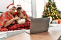 Two hispanic men couple watching movie sitting by christmas tree at home Royalty Free Stock Photo