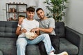 Two hispanic men couple watching movie sitting on sofa at home Royalty Free Stock Photo