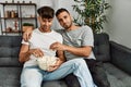 Two hispanic men couple watching movie sitting on sofa at home Royalty Free Stock Photo