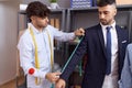 Two hispanic men tailor measuring sleeve jacket client at atelier