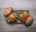 Two home burgers with chicken in mustard sauce, arugula, tomatoes on a cutting board on wooden rustic background top view close up Royalty Free Stock Photo