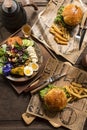 Two homemade beef burgers with potato fries and fruit and vegetable salad old wooden table background board in a rustic. Side view