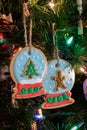 Two homemade snow globe sugar cookie ornaments hanging from a Christmas tree.