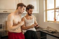 Two homosexuals look at smartphone, in kitchen