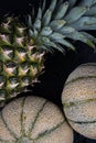 Two honeydews and a fresh pineapple on a black surface. Royalty Free Stock Photo