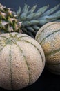 Two honeydews and a fresh pineapple on a black surface. Royalty Free Stock Photo