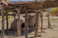 Two hornos-traditional earthen ovens- underneath a drying rack with a childs doll left on the corner - Homes of the Ute Pueblo in