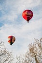 two hot air balloons flying in the sky between a tree Royalty Free Stock Photo