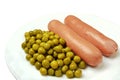 Two hot boiled sausages with canned green peas are served for evening meal Royalty Free Stock Photo