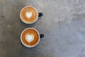 Two hot cups of cappucino on concrete background. Heart shape art latte symbol of love. Royalty Free Stock Photo