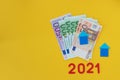Two house models on a bundle of euro banknotes on a yellow background. Home, real estate or mortgage concept. Soft focus. Copy