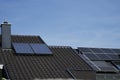 Two house roofs: The front roof is covered with solar thermal panels, the house behind is equipped with photovoltaic panels. Royalty Free Stock Photo