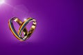 Two hovering wedding rings with rainbow colors isolated on purple background. Equal rights movement for gay marriages and gender