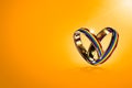 Two hovering wedding rings with rainbow colors on orange background. Equal rights movement for gay marriages and gender