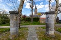 Two huge thick pillars with a pedestrian path, houses and bell tower of St. Michael Abbey churc