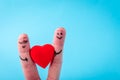 Two human fingers with heart on blue background. A happy couple in love with painted smiley and hugging Royalty Free Stock Photo