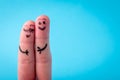 Two human fingers with heart on blue background. A happy couple in love with painted smiley and hugging Royalty Free Stock Photo