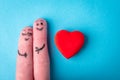 Two human fingers with heart on blue background. A happy couple in love with painted smiley and hugging Royalty Free Stock Photo