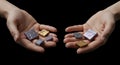 Two human hands, palms up, display an assortment of square stones. The stones