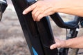 Two human hands touching the electric motor of a black electric bicycle to remove it and recharge it