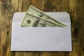 Two hundred dollars in one hundred dollar in cash in white envelope is lying on brown wooden table. Saving money or corruption and Royalty Free Stock Photo