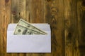 Two hundred dollars in one hundred dollar in cash in white envelope is lying on brown wooden table. Saving money or corruption and Royalty Free Stock Photo