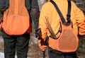 Two Hunters Walking with Shotguns and Tail Feathers Sticking Out of Their Pouch.