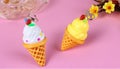 Two ice cream cone earrings on a pink background