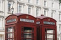 Two iconic British red telephone boxes against buildings, selective focus