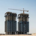 Twin skyscrapers under construction with cranes and scaffolding against a clear sky building Royalty Free Stock Photo