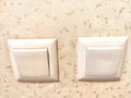 Two identical switches on a cream background. Twin Light Switches on Textured Wall Royalty Free Stock Photo