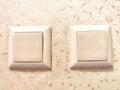 Two identical switches on a cream background. Twin Light Switches on Textured Wall Royalty Free Stock Photo