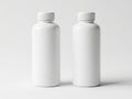 Two identical white plastic bottles with silver caps standing side by side on a plain white background Royalty Free Stock Photo