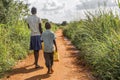 Two impoverished Ugandan kids carrying jerry cans on a walk to get water.