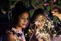 Indian female friends holding illuminated string lights in the evening