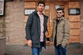 Two indian guys on jackets posed outdoor against door of pub Royalty Free Stock Photo