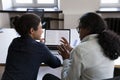 Two Indian office employees sharing laptop at work table