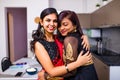 two indian women with bindi on the forehead hugging in living room