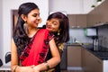 two indian women with bindi on the forehead hugging in living room