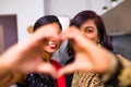 two indian women with bindi on the forehead hugging in living room