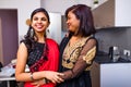 two indian women with bindi on the forehead hugging in living room