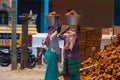 Two Indian women carry heavy bricks on their heads in traditional clothes. View from the back. Use of female labor at