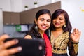 two indian women in saree talk with family by phone video chatting at living room in home Royalty Free Stock Photo