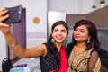 two indian women in saree talk with family by phone video chatting at living room in home Royalty Free Stock Photo