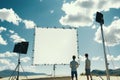 Two individuals observing a blank screen on a sunny day in a mountainous setting