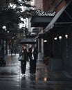 two people walking in the rain holding umbrellas and walking down the street Royalty Free Stock Photo