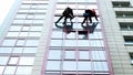 Two industrial climbers are washing, cleaning facade of a modern office building Royalty Free Stock Photo