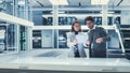 Two Industrial Engineers Gathered at a Table. Young Multiethnic Female and Male Scientists Usi